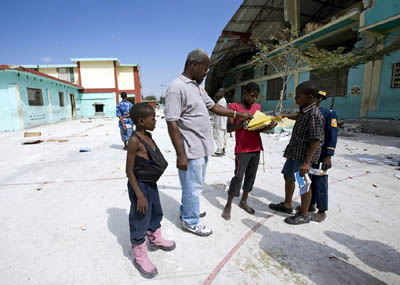 22 gennaio 2010 - Don Pierre Lephne davanti alle rovine dell`opera salesiana Enam con alcuni bambini di strada.